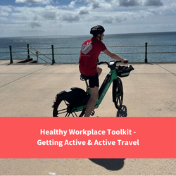 healthy cornwall staff member sat on bike on penzance promenade, text reads "Healthy Workplace Toolkit - Getting Active and Active Travel"