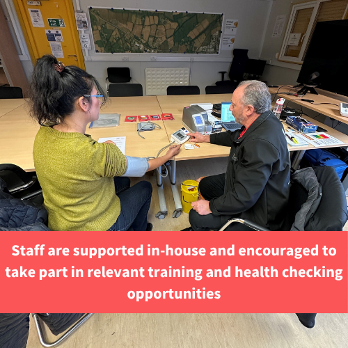 person having blood pressure taken by healthy cornwall staff member, text reads "Staff are supported in-house and encouraged to take part in relevant training and health checking opportunities"