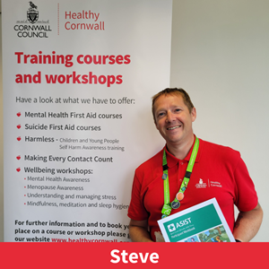 picture of Steve Webb, a member of the training team at healthy cornwall, stood next to a training banner, holding a training booklet and smiling