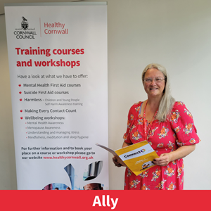 picture of Ally Green, training team lead at healthy cornwall, stood next to a training banner andholding a training booklet.