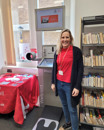 image of a healthy cornwall staff member stood next to a health check kiosk