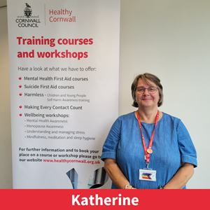 picture of Katherine Castle, a member of the training team at healthy cornwall, stood next to a training banner and smiling