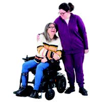 a woman in a wheelchair having a hug from a carer